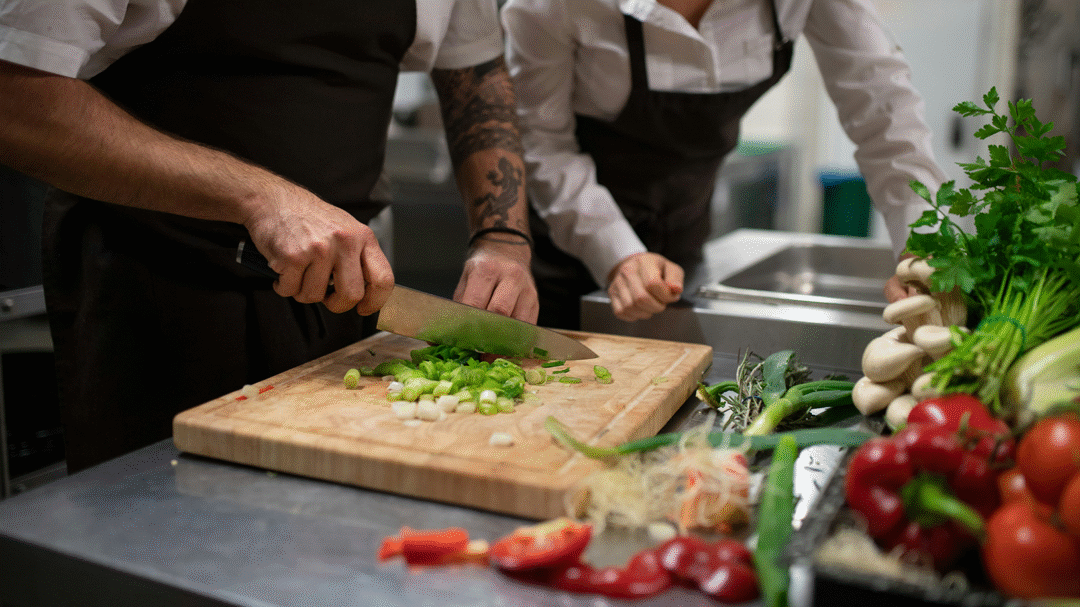 Chef preparing food in a commercial kitchen, demonstrating food safety and hygiene practices powered by Navitas Safety solutions