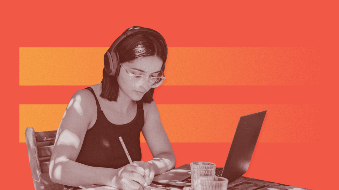 Professional working on a laptop while writing in a notebook