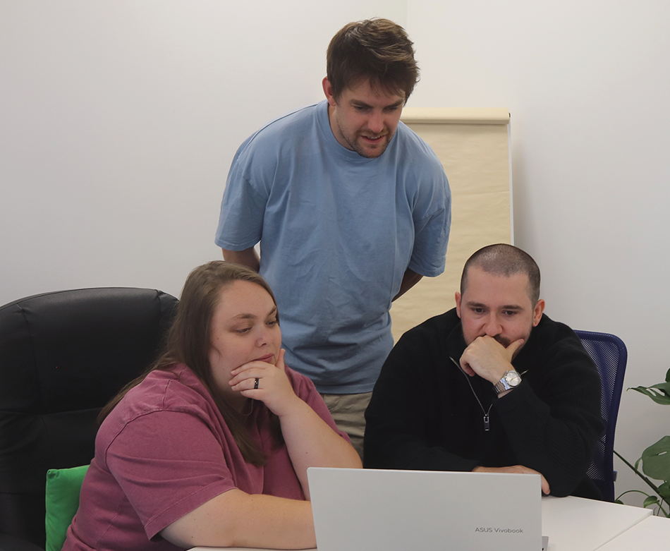 Three Repeat Digital colleagues collaborating around a laptop in a bright office meeting space
