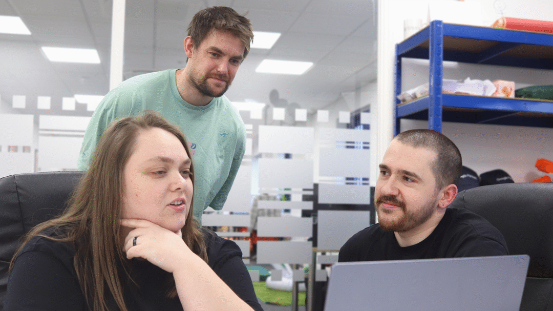 Three Repeat Digital colleagues collaborating around a laptop in a bright office meeting space