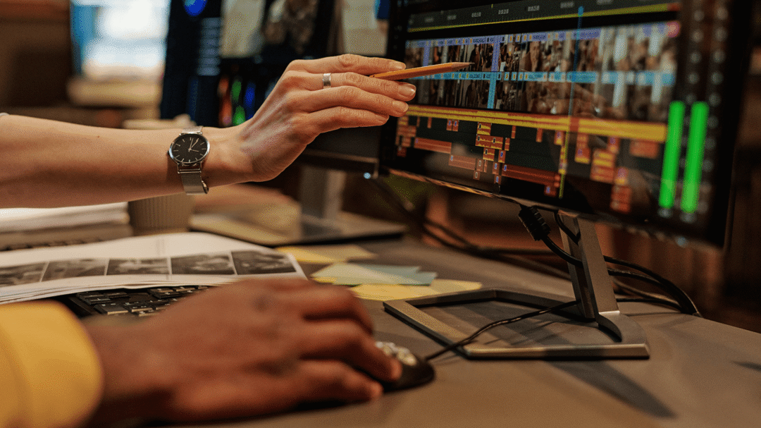 Person editing a video timeline on a computer monitor in a creative software workspace