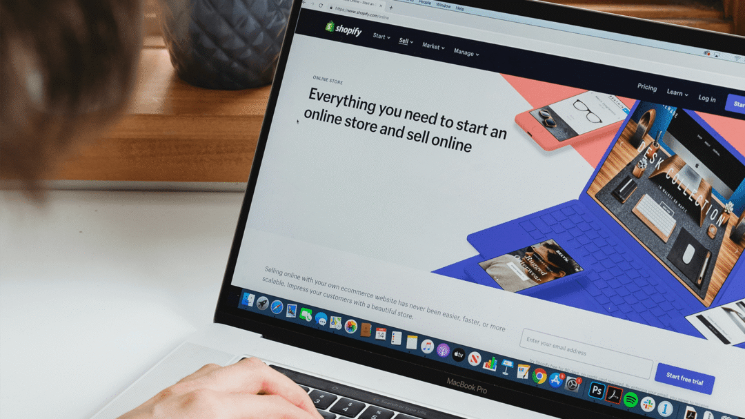 Person using a laptop showing the Shopify homepage