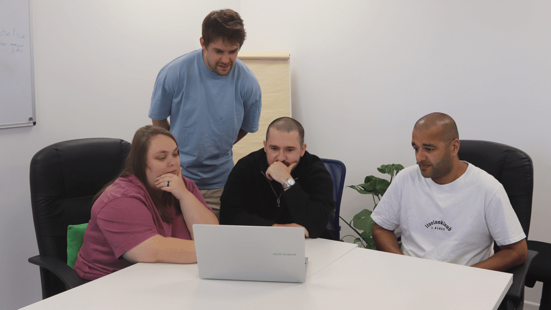 Four Repeat Digital colleagues collaborating around a laptop in a bright office meeting space