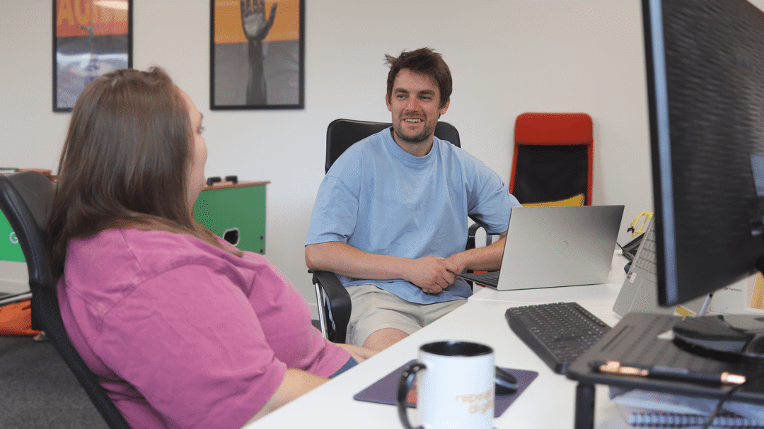 Two Repeat Digital employees chatting at their desks